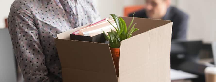 A person carrying a box as they leave their job.