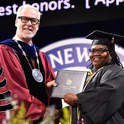 SNHU President Paul LeBlanc, left, handing student speaker Patria Evans, right, her diploma.