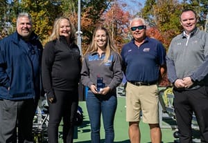 Former women’s tennis player Amber (Chandronnait) Robins standing between four people after being inducted into the NE10 Hall of Fame.
