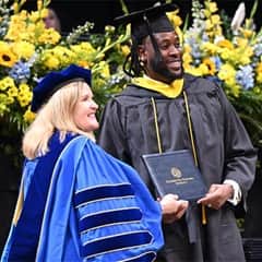 SNHU President Lisa Marsh Ryerson posing while handing diploma to graduate