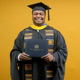 Aaron Davenport, a 2025 master's in finance graduate from SNHU, wearing a cap and gown and holding his diploma.