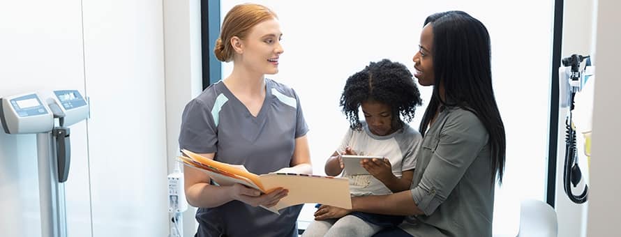 A nurse practitioner talking to a woman and her young daughter.