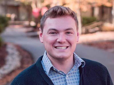 Alec Biron, who earned degrees from SNHU in 2017 and 2021, wearing a button down shirt and a cardigan sweater.