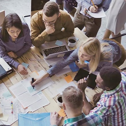 A group of students sit at a table discussing the importance of critical thinking