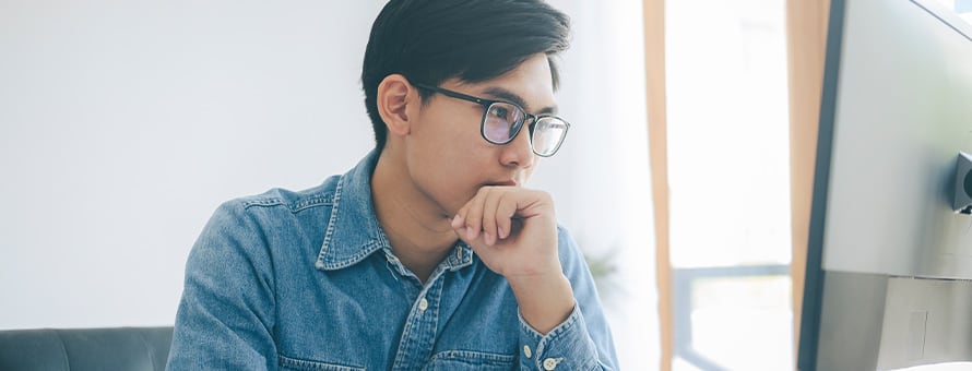 A man looks at his computer screen researching an associate of science degree