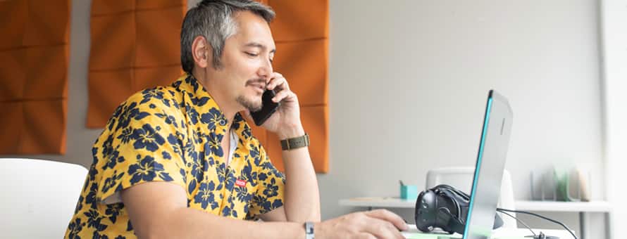 Derald Wise sitting down on his laptop working on his BA degree while on a phone call