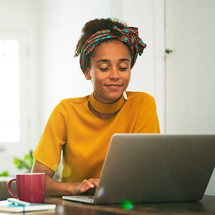A person using a laptop, researching how long it takes to get her bachelor's degree online.