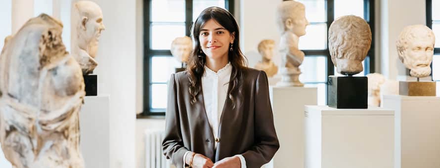 A historian standing in the middle of a room in a museum full of statues