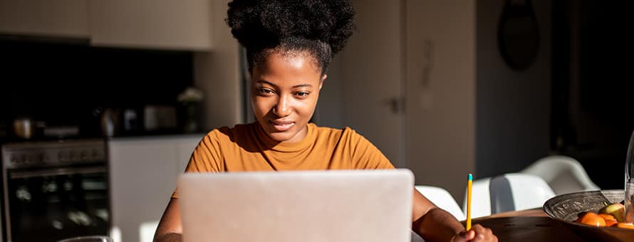 A student sitting at her desk working on her laptop researching Black History Month