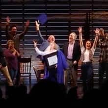 Emily Walton, surrounded by cast members, tossing her graduation cap in the air.
