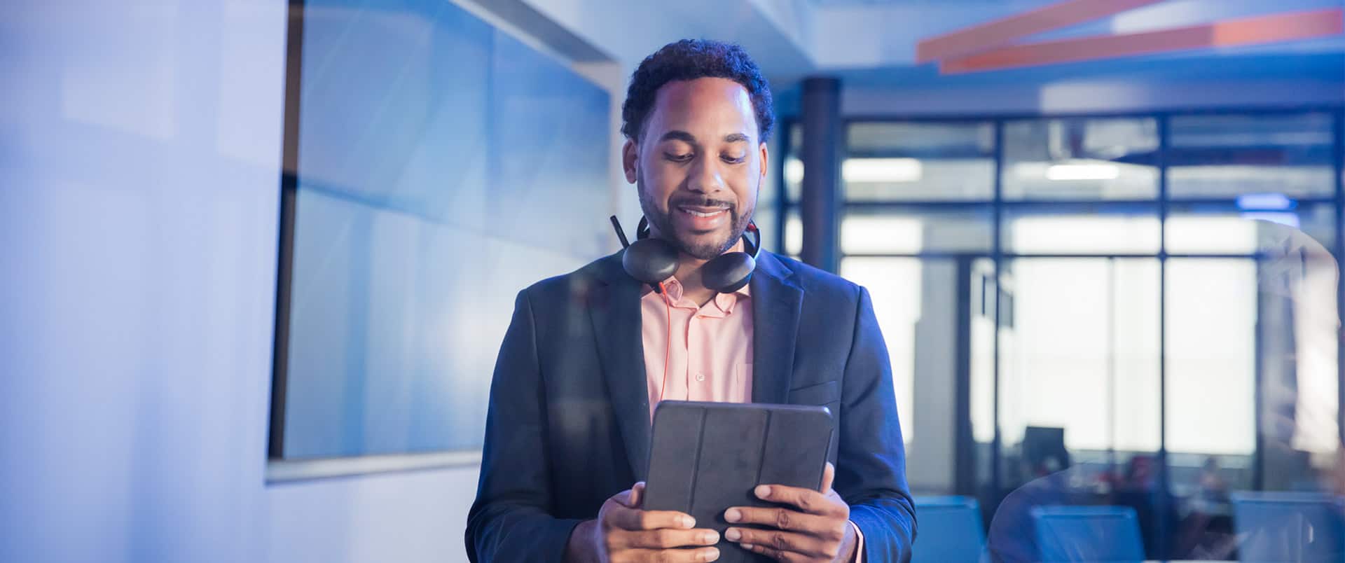 Gary Walker, who graduated from SNHU in 2021, holding a tablet and wearing a blue sport coat with headphones around his neck.