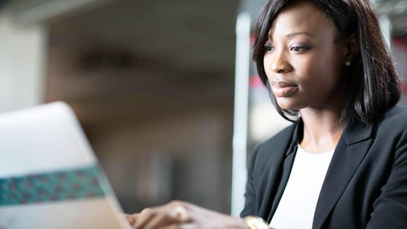 Sierra Ingram, who earned her degree from SNHU in 2018, wearing a dark blazer and typing on a laptop computer