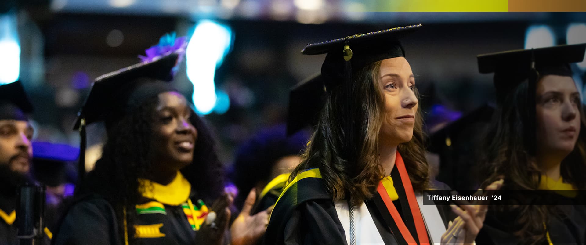 Tiffany Eisenhauer, who earned her bachelor's in sport management from SNHU in 2024, wearing her cap and gown at the clapping her hands at the SNHU commencement ceremony.