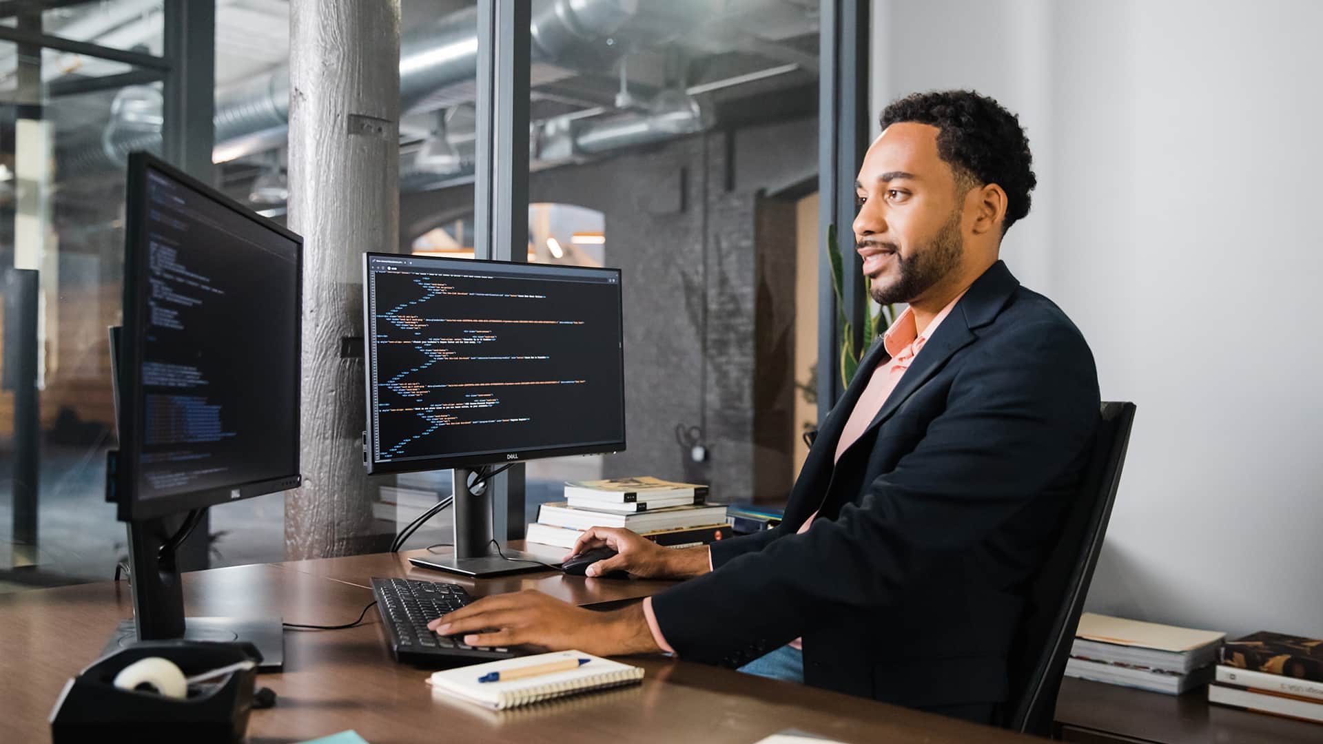 Gary Walker, who earned his degree from SNHU in 2022, sitting at a desk with two computer monitors in an office using a mouse and keyboard.