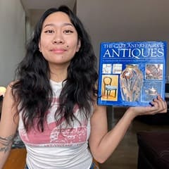 Carlene Estigoy, an SNHU bachelor's in psychology graduate, holding "The Care and Repair of Antiques" by Paul Oakley.