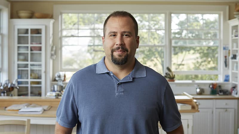 Raymond Gammon, who earned his degree from SNHU in 2020, wearing a blue polo shirt standing in his kitchen.
