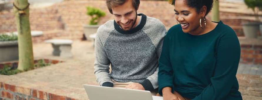 Two students working together on a laptop.