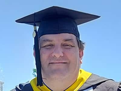 Christopher McGinnis, who earned his online MS in Organizational Leadership degree in 2023, wearing his cap and gown.