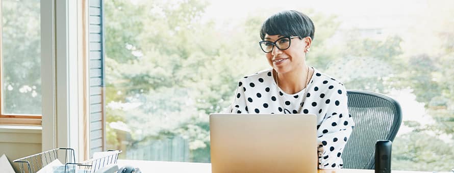 An employee sitting at her desk working on her laptop