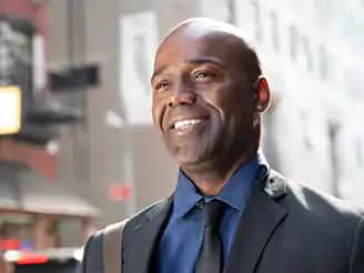 Jean Besson, 2014 graduate of the online bachelor's in business administration program, standing outside and smiling.