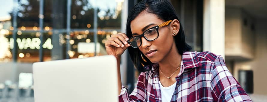 A person sitting by a window, researching certificate programs on a laptop.