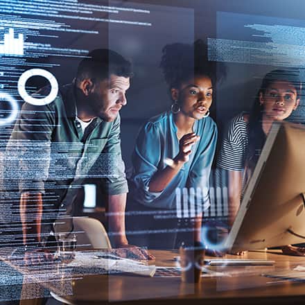 A man and two women looking at a monitor working on a computer science project 