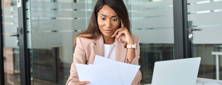 A woman sitting at her desk comparing a curriculum vitae and a resume
