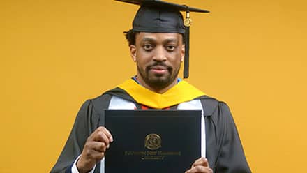 2025 online cybersecurity program graduate Josiah Lee holding his SNHU diploma.
