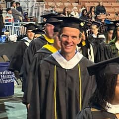 Dale Stephanos processing out of his SNHU Commencement ceremony, donning a graduation cap and gown.