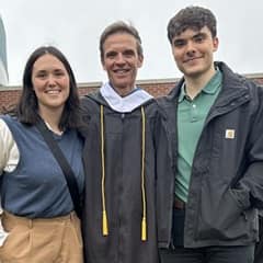 Dale Stephanos in his graduation gown with his two kids on either side of him.
