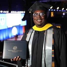 Darryl Johnson at the SNHU Arena in Manchester, New Hampshire, dressed in his graduation cap and gown.