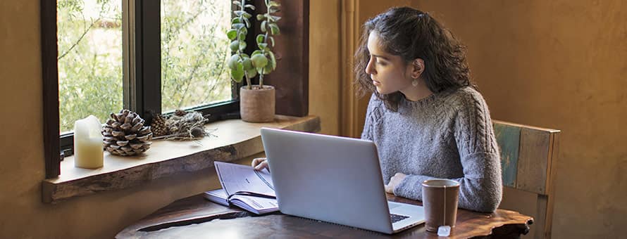 A person with a laptop and notebook, considering the differences between a bachelor's degree and a master's degree.