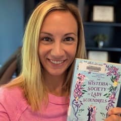 Dr. Kelsey Deters, a clinical faculty member of undergraduate nursing programs at SNHU, holding "Wisteria Society of Lady Scoundrels" by India Holton.