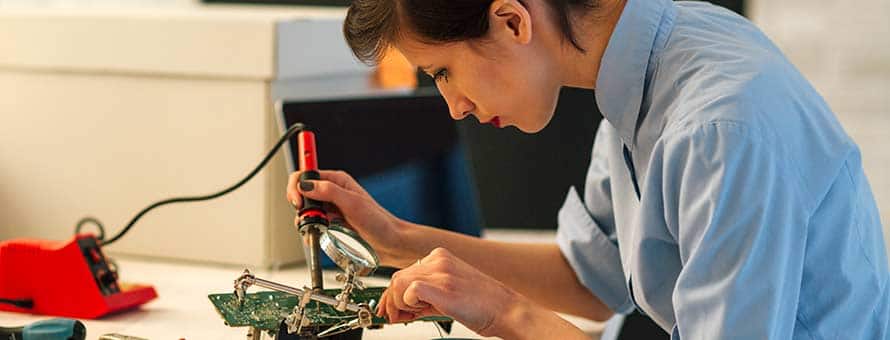 An electrical engineer using a soldering tool to build an electrical component