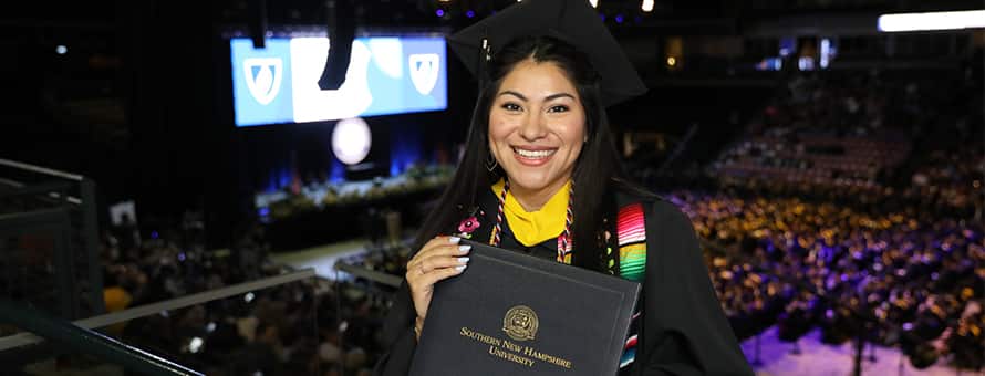 Eliana Cornejo holding her diploma at her SNHU commencement ceremony