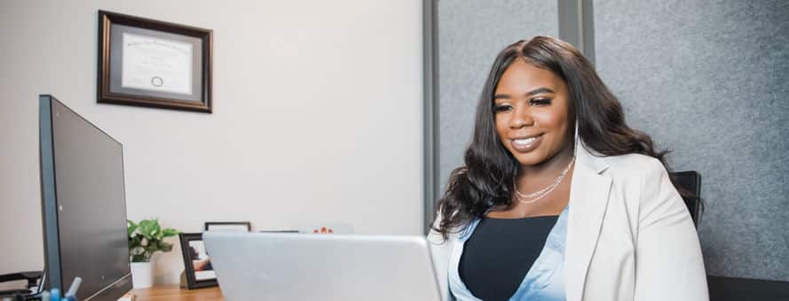 Tanzania Fair, 2020 online MBA graduate, sitting at a desk and working on a laptop.