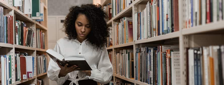 A woman with an English literature degree reading a book in a library