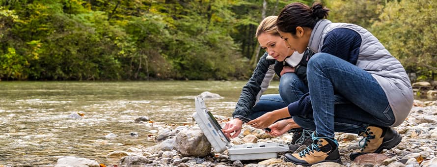 Two environmental science students working along the side of a river