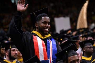 Pedro Borges, a recent SNHU graduate who earned his BS in Business Administration, in his cap and gown at commencement, waving.