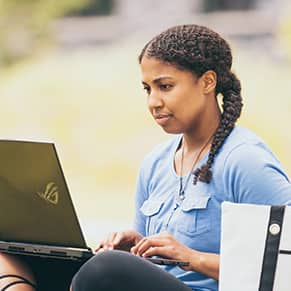 SNHU student on their laptop in a park.