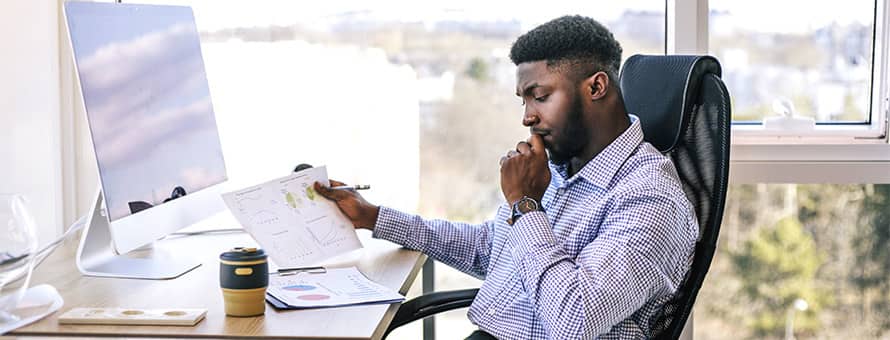 A man looks at a series of charts contemplating the difference between finance vs. accounting