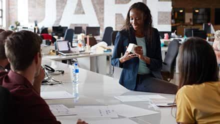 Six marketing professionals sitting around a white office table, discussing a product.