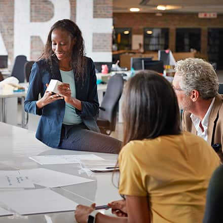 Three marketing professionals sitting around a white office table, discussing a product.