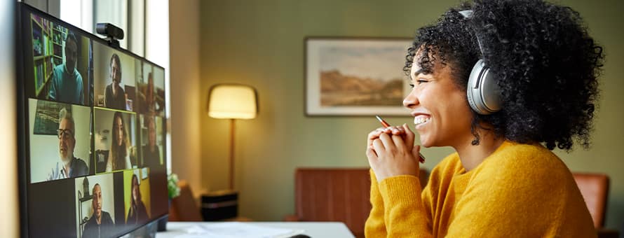 A woman working from home sitting at her desktop on a work video call. 