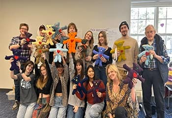 A group of 15 volunteers holding stuffed animal bears, an SNHU Global Days of Service project that gifts hand-sewn bears to children living through difficult circumstances.