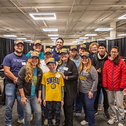 A group of 13 Global Days of Service volunteers, including SNHU President Lisa Marsh Ryerson, center, who supported the New Hampshire Food Bank.