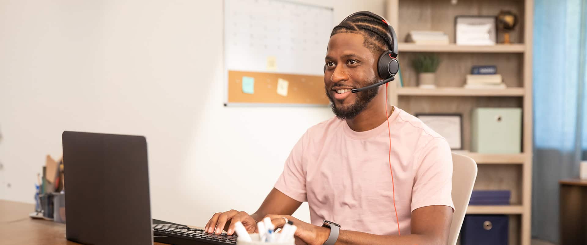 Matt Seawright, who earned his degree from SNHU in 2019, sitting at a desk in an office wearing a headset with a microphone and typing on a keyboard.