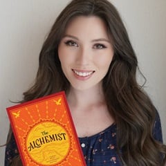 Haley-Grace McCormick, an SNHU bachelor's in creative writing and English graduate, holding "The Alchemist" by Paulo Coelho.