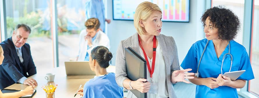 A healthcare administrator speaking with a doctor in a medical office.
