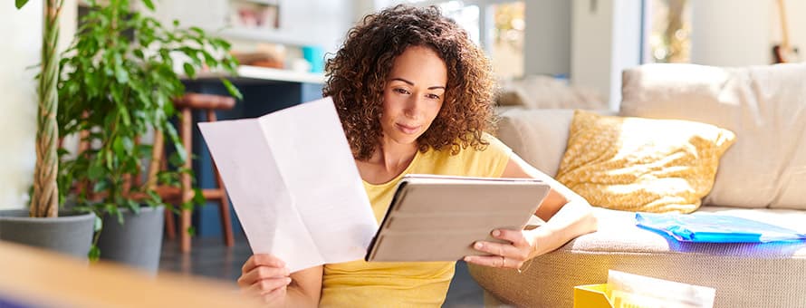 An online student learning how financial aid works as she holds her financial aid offer letter and reviews information on a tablet.